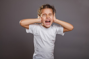 Teen girl screams closes ears gray background