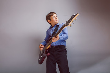 teenager boy brown hair European appearance playing guitar on a
