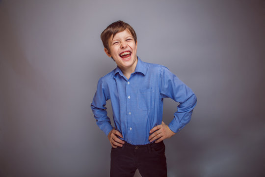 teenager boy enjoys laughing on gray background