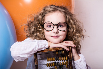 Funny, clever curly teen girl in glasses with wooden abacus on t