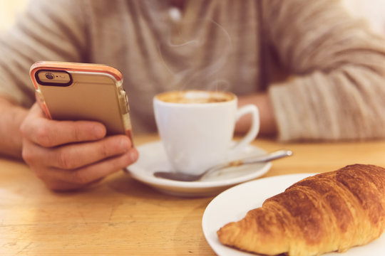 unrecognisable man drinking coffee and holding smart phone