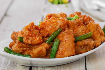 pieces of chicken in batter with spicy sauce and green beans