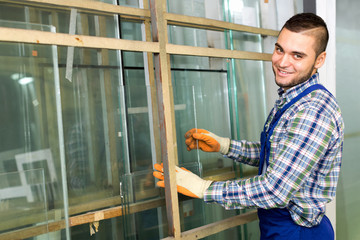 Worker measuring glass at factory