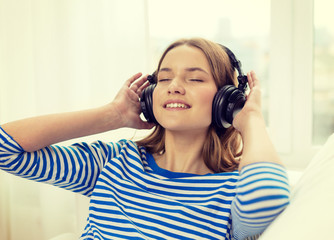 Naklejka premium smiling young girl in headphones at home