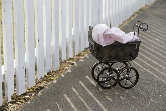 Vintage Stroller In Front Of White Fence