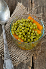 canned peas and carrots on wooden surface