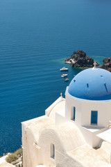Fototapeta na wymiar Blue cupola of whitewashed Oia church in Santorini