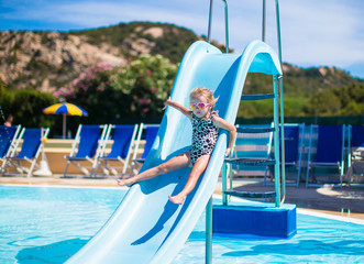 Little girl on water slide at aquapark on summer holiday