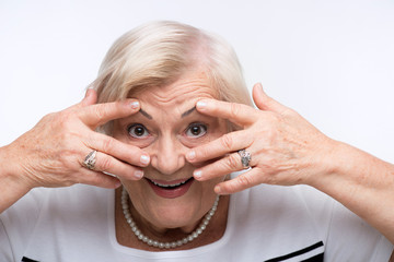 Elderly woman closes her mouth, ears and eyes with hands