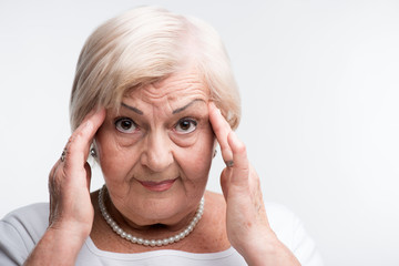 Elderly lady touching her head with fingers