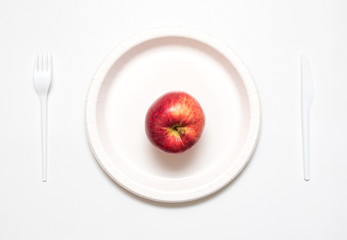 Red apple on white plate with knife and fork, 