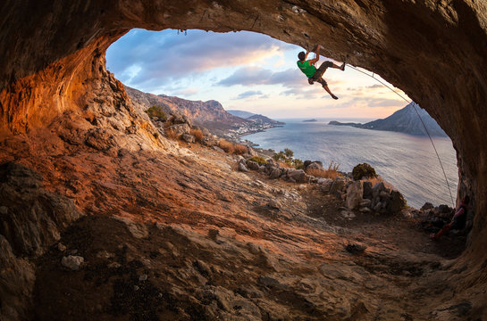 Young man lead climbing in cave before sunset