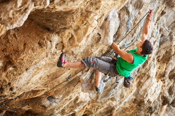 Rock climber going to clip rope while lead climbing