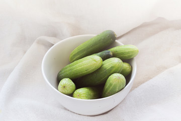 fresh green cucumbers on white fabric background