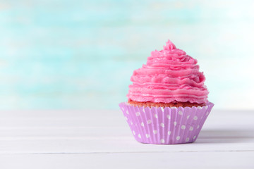 Delicious birthday cupcake on table on light blue background