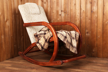 Obraz na płótnie Canvas Rocking chair covered with plaid on wooden wall background