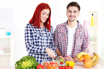Happy couple preparing  vegetable salad in kitchen