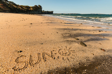 sun with smiley written in sand on beach in New Zealand