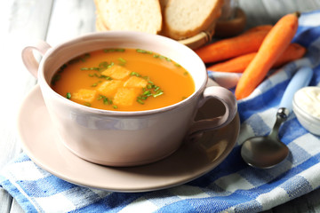 Carrot soup, cream and spoon, on  color wooden background