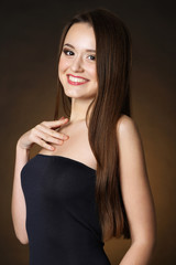 Naklejka premium Beautiful young woman with long hair on dark brown background