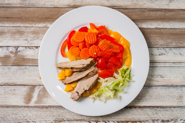 Roast duck slices with orange and vegetables, top view