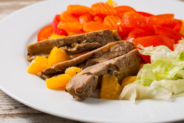Roast duck slices with orange and vegetables, closeup