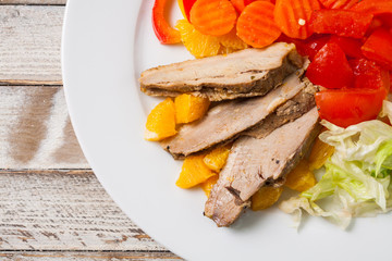 Roast duck slices with orange and vegetables, closeup