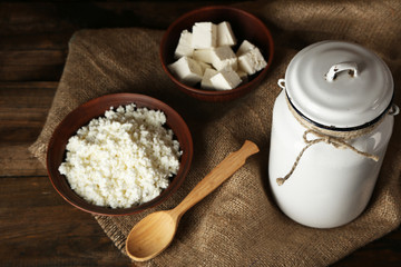 Milk can with cottage cheese on wooden background