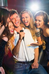 Happy friends singing karaoke together - obrazy, fototapety, plakaty