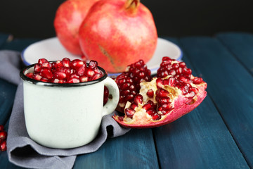Juicy ripe pomegranate on wooden table, on dark background