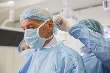 Medical student tying professors surgical mask