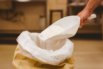 Fototapeta na wymiar Baker scooping flour out of sack