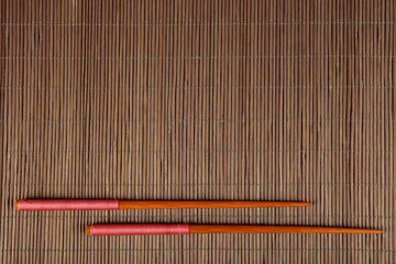 Pair of chopsticks on bamboo mat background