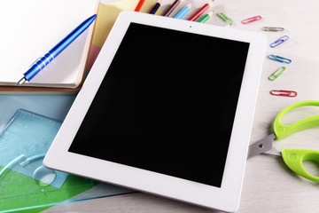 Tablet PC with office supplies on desktop background