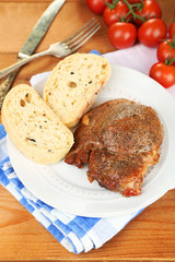 Roasted meat and vegetables on plate, on wooden table