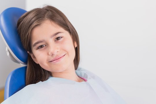 Smiling young patient sitting in dentists chair