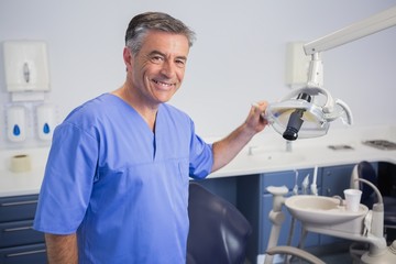Portrait of a friendly dentist holding light - Powered by Adobe