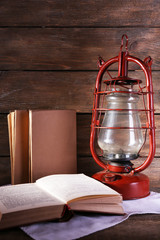 Fototapeta na wymiar Kerosene lamp with books on rustic wooden background