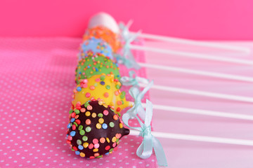 Sweet cake pops on table on pink background