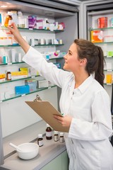 Junior pharmacist taking medicine from shelf
