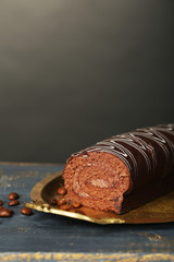 Delicious roll cake on wooden table, on dark background