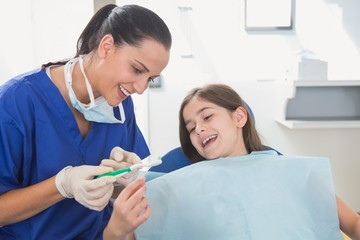 Smiling pediatric dentist explaining to young patient