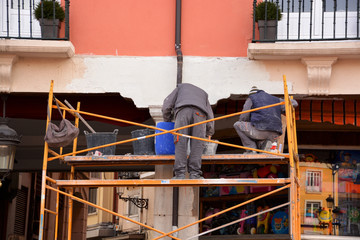 obreros trabajando encima de un andamio