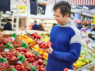 Man chooses bell peppers in store
