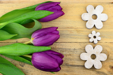 purple tulips and white wooden flowers on old wood