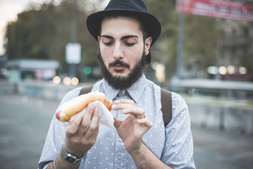 young handsome hipster gay modern man eating hot dog