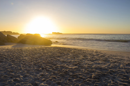 Sandy beach at sunset with rocks in the foreground