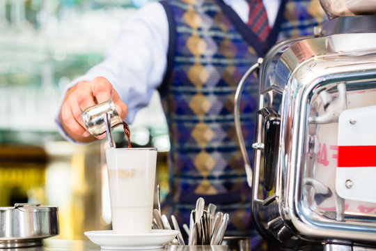 Barista im Cafe gießt Espresso in latte macchiato