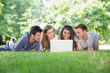 Happy students using laptop outside