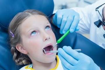 Male dentist examining girls teeth